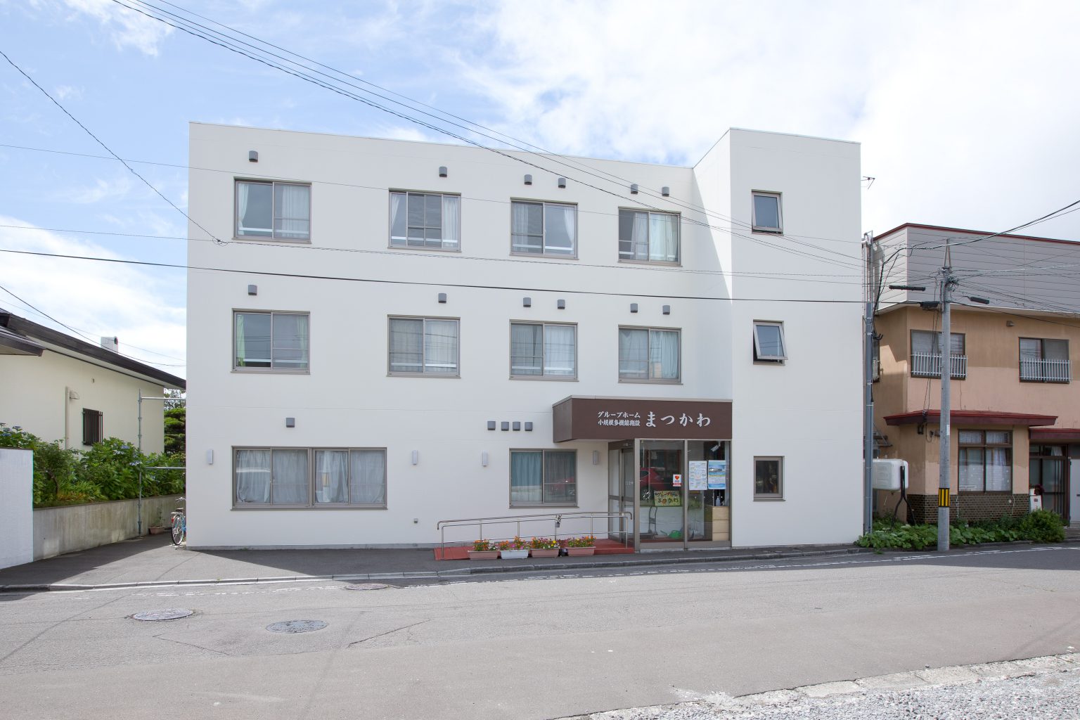 白い3階建ての介護施設の建物外観。玄関には施設名の看板が見える。
